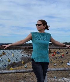 a woman standing next to a fence covered in padlocks