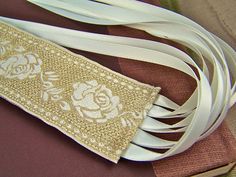 a white ribbon with flowers on it sitting on top of a piece of cloth next to other fabric