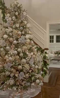 a decorated christmas tree in the corner of a living room with stairs leading up to it