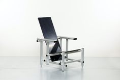 a black chair sitting on top of a white floor next to a metal frame structure