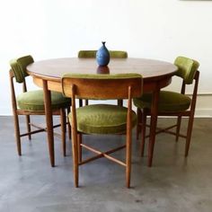 a table with four chairs and a vase sitting on it's top, in front of a white wall