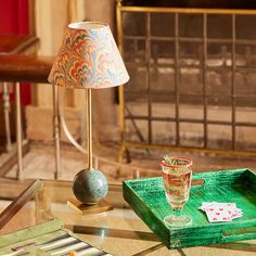 a green tray with a glass on it next to a lamp and a card holder