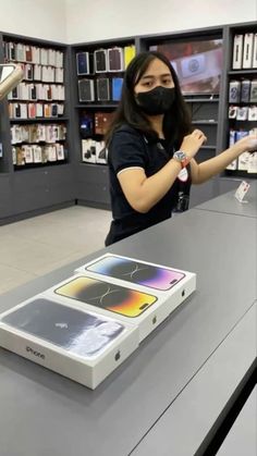 a woman wearing a face mask standing in front of an apple store display with the box open