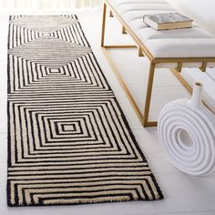 a long black and white rug in the middle of a room next to a bench