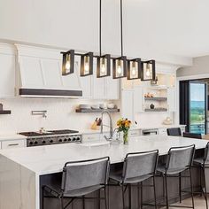 a large kitchen with an island and lots of chairs around the counter top, in front of a sliding glass door that leads to a balcony