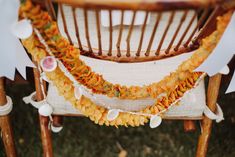 a chair decorated with yellow flowers and white paper garlands on the back of it