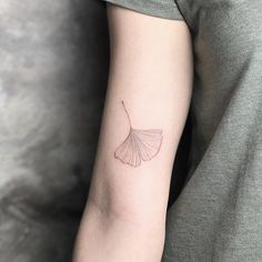 a woman's arm with a small ginkoke leaf tattoo on the left inner arm