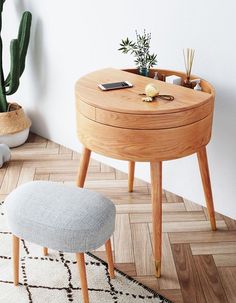 a small wooden table with a phone on it and a plant in the corner next to it