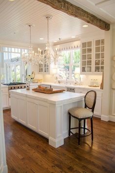 a large kitchen with white cabinets and wooden floors