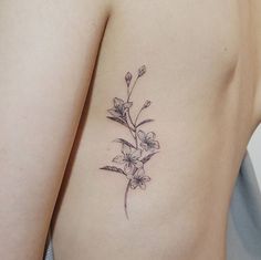 a small flower tattoo on the back of a woman's right arm and shoulder