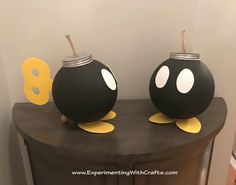 two black vases sitting on top of a wooden table with yellow and white decorations