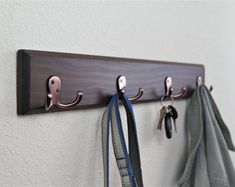 a coat rack with three coats hanging from it's hooks and two pairs of ties