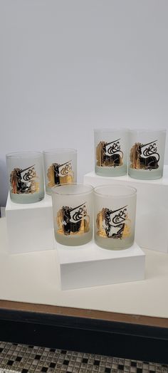 four glass cups with designs on them sitting on a white counter top next to each other