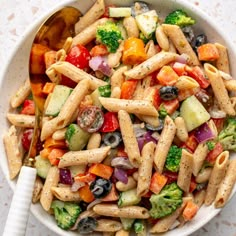 a pasta salad with broccoli, cucumbers, tomatoes and olives