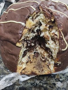 a chocolate covered doughnut with white icing on a marble counter top, cut in half to show the inside