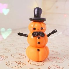 a small orange snowman with a black hat and mustache