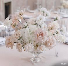 a vase filled with white and pink flowers on top of a table covered in plates