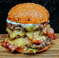 a cheeseburger with meat, lettuce and tomato on a wooden cutting board