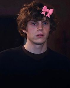 a young man with a pink bow in his hair