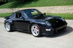 a black sports car parked in front of a brick wall