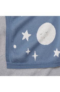 a blue blanket with white stars and a sleeping moon on the front, it's made out of cotton