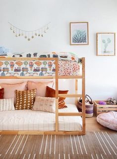 a bunk bed with pink and gold pillows in a room filled with pictures on the wall