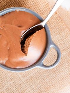 a spoon in a cup filled with chocolate frosting on top of a burlap cloth