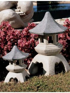 three stone lanterns sitting in the grass near flowers