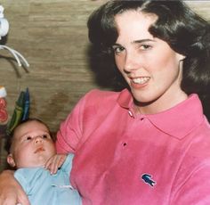 an old photo of a woman holding a baby in her lap and smiling at the camera