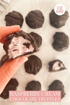 a hand holding a chocolate truffles with raspberry cream on it and the text overlay says, raspberry cream chocolate truffles