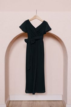 a black dress hanging on a wooden hanger