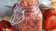 a glass jar filled with food sitting on top of a cutting board next to strawberries