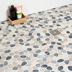 a bath room with a toilet and a stone flooring pattern on the shower stall