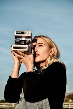 a woman holding an old camera up to her face