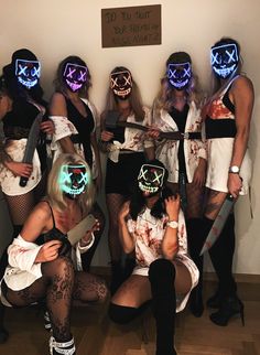 a group of women dressed in costumes with neon masks on their faces and holding knives