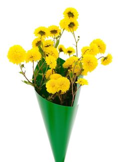 a green vase filled with yellow flowers on top of a table