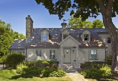 an image of a gray house with trees and bushes in the foreground, on a computer screen