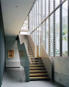 there is a stair case in the middle of this room with large windows on both sides