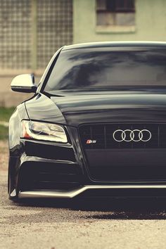 the front end of a black car parked in a parking lot