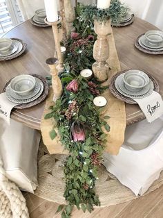 the table is set with candles, plates and greenery on it's sides