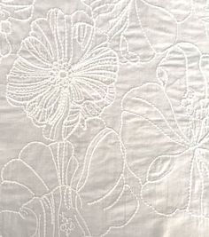 a white tablecloth with flowers and leaves on it's side, as well as an embroidered design