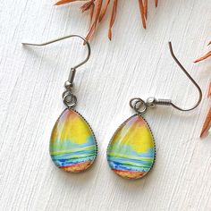 These gorgeous earrings feature a print of one of my original paintings glazed under glass, they measure approximately 0.50 x 0.70 inches and both the earwire and the bezel are stainless steel. Nickel-free Teardrop Artsy Earrings, Artistic Teardrop Earrings With Artistic Design, Artistic Teardrop Earrings, Artsy Teardrop Earrings With Ear Wire, Artsy Teardrop-shaped Earrings, Artistic Yellow Teardrop Earrings, Artistic Yellow Teardrop Jewelry, Adjustable Teardrop Artsy Earrings, Artistic Teardrop Earrings With Ear Wire