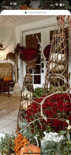 an arrangement of flowers and pumpkins in front of a house