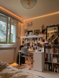 a bedroom with lights on the ceiling and a desk in front of a window, next to a bookshelf