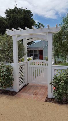 a white fence with a brick walkway leading to the front door and side yard area