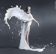 a woman is dressed in white and splashing milk