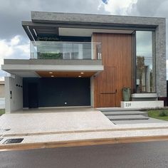 a modern house with large wooden doors and steps leading up to the front door on a cloudy day