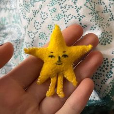 a hand holding a small yellow star with a face drawn on it's side