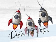 three felt rockets are hanging from strings on a white wooden background with the words digital felt patterns written below them