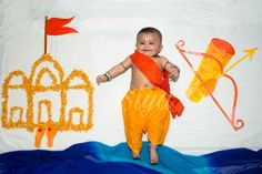 a baby is standing in front of a backdrop with kites and other decorations on it